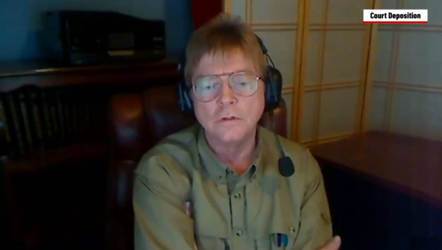 A still from a video of Dr. Michael Shiver giving a legal deposition. Shiver was deposed remotely, and is wearing a headset with a microphone.