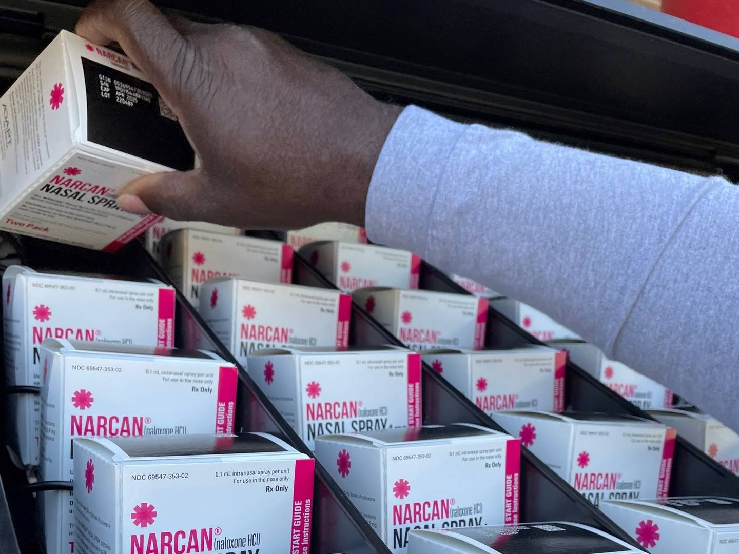 Boxes of two-doses of Narcan are lined up in the dispenser slots of a vending machine as someone loads the final box into the row.