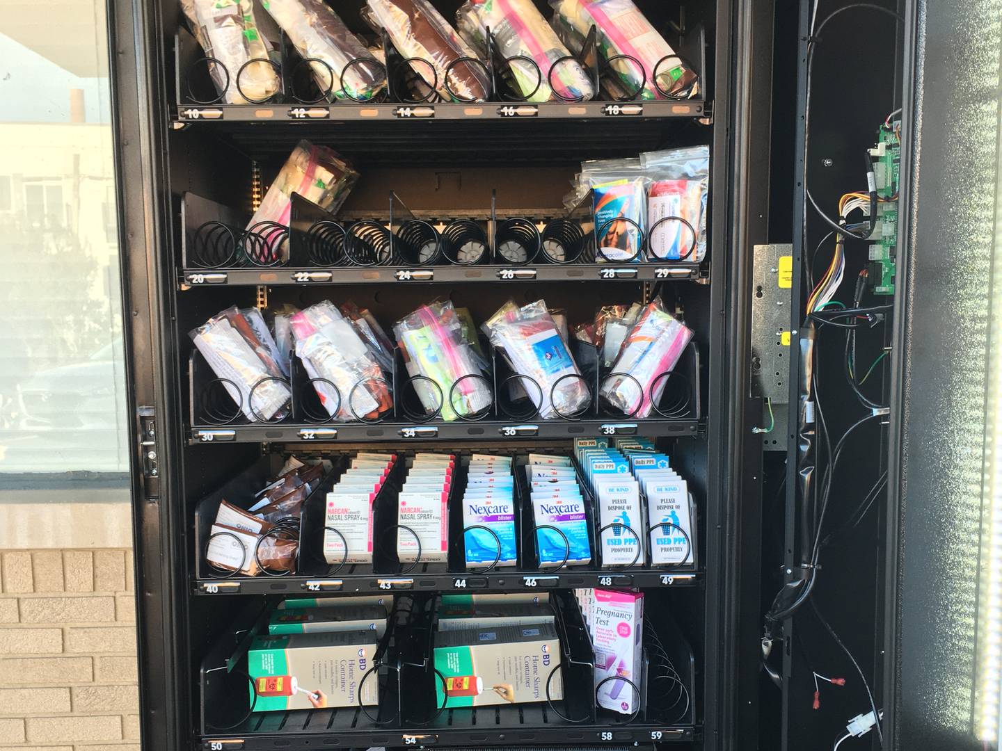 A photo of an open vending machine showing the contents, which include hygiene items and overdose reversal kits.