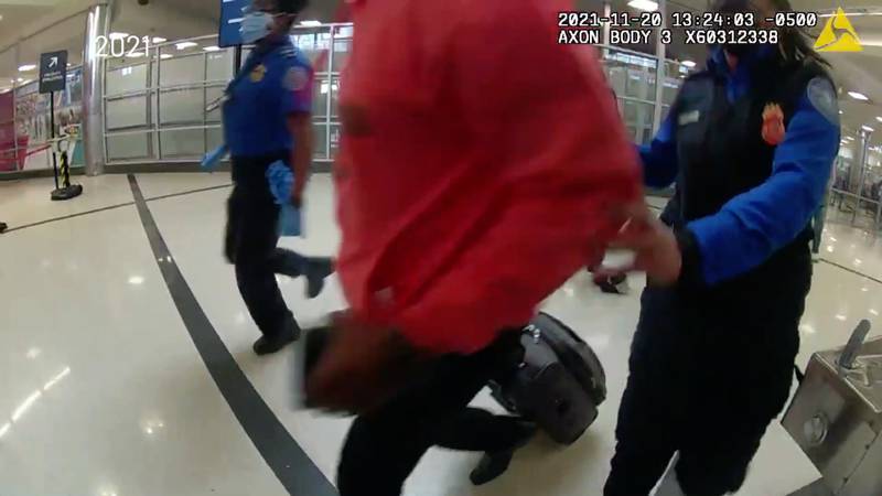 An image from a law enforcement officer's body camera video show TSA officers helping a passenger flee. The two officers and the passenger are shown running away from the TSA checkpoint equipment.